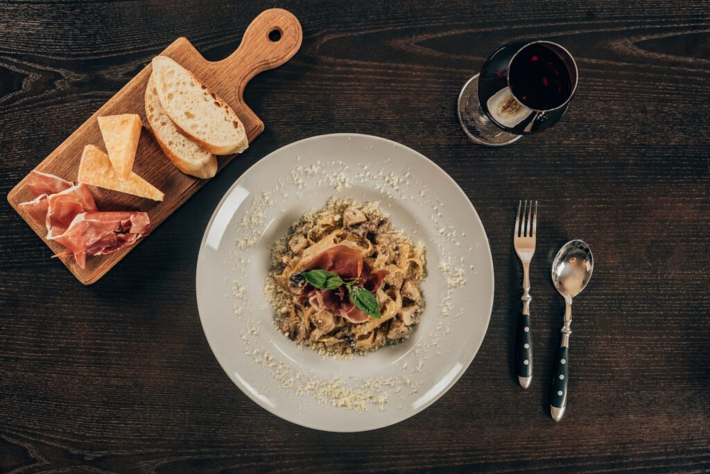 top view of pasta with meat and glass of red wine on table