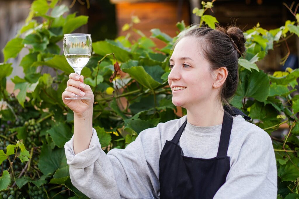 Young woman winemaker checking the white wine quality on the vineyard. she is winemaking